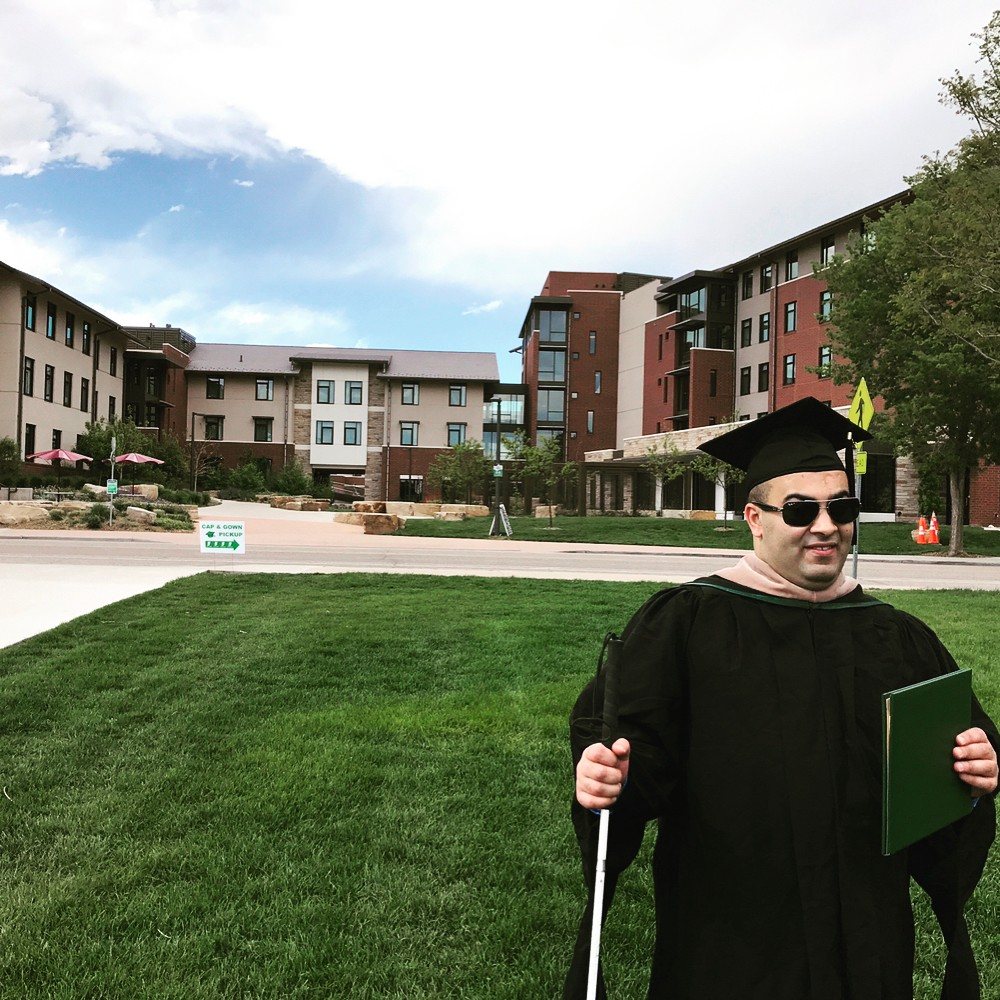 Noah in academic regalia holding his diploma after graduation at Colorado State University